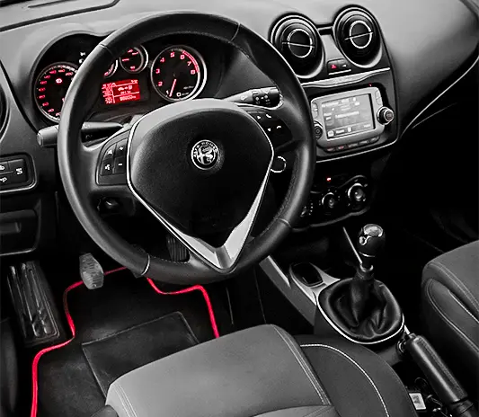 Interior view of an Alfa Romeo dashboard and steering wheel, serviced at Exotic Auto Services workshop.